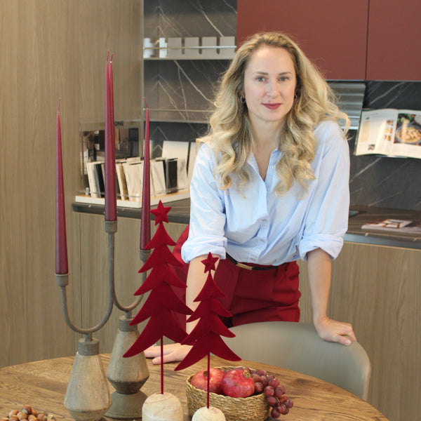 Woman standing next to a wooden table with decorative items in an indoor setting